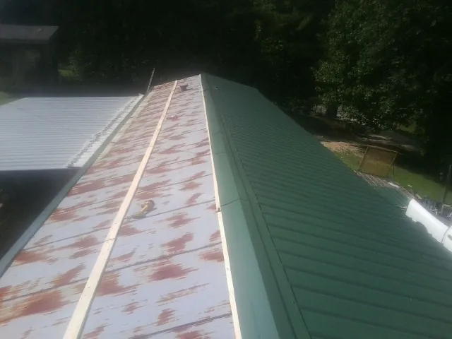 Old rusted panels beside newly installed green metal roofing — Wind Damage Roof Repair by Roofing Brothers in Moscow